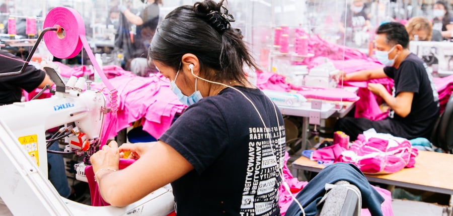 Workers efficiently operating industrial sewing machines in a manufacturing plant certified by SEDEX and WRAP, showcasing teeone's commitment to ethically-sourced production.